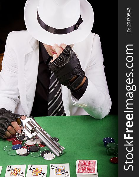 View of a gangster man playing some cards and poker, holding a gun. View of a gangster man playing some cards and poker, holding a gun.