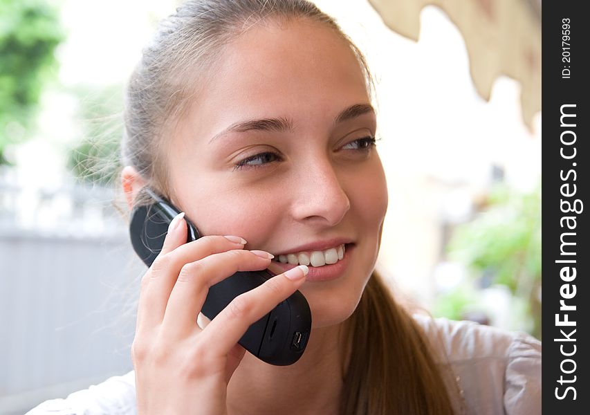 Portrait of charming woman with mobile phone outdoor is speaking and smiling, enjoying the conversation. Portrait of charming woman with mobile phone outdoor is speaking and smiling, enjoying the conversation