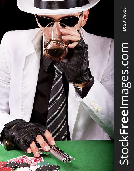 View of a gangster man playing some cards and poker, having a drink. View of a gangster man playing some cards and poker, having a drink.