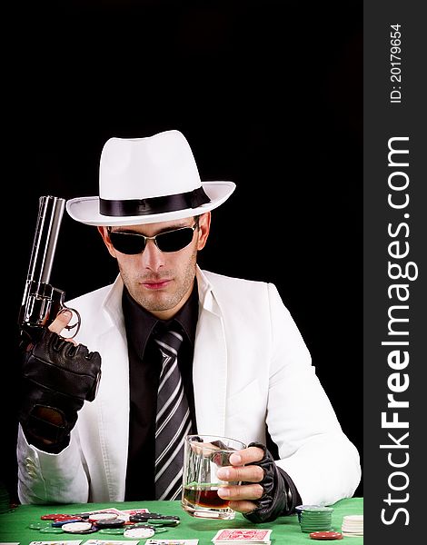 View of a gangster man playing some cards and poker, holding a gun. View of a gangster man playing some cards and poker, holding a gun.