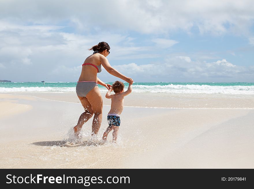 Photo of a young mother running with her little son on a white sand tropical beach. Photo of a young mother running with her little son on a white sand tropical beach