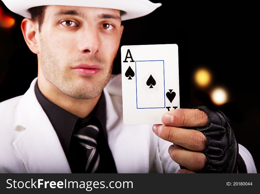 View of a white suit man with hat, holding an ace card.
