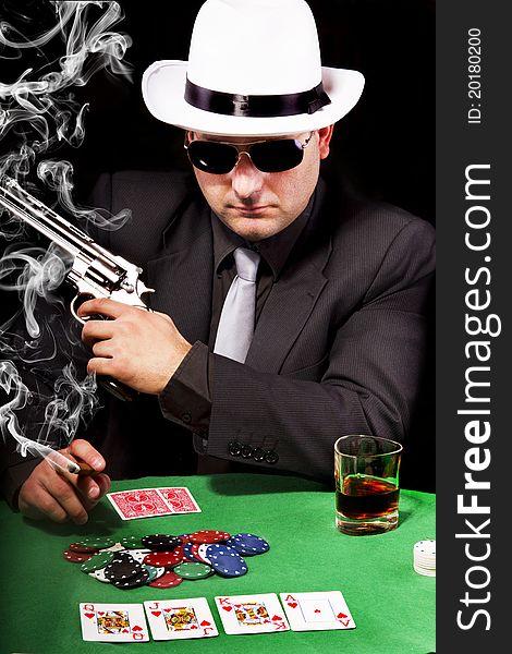 View of a gangster man playing some cards and poker, smoking a Cuban cigar. View of a gangster man playing some cards and poker, smoking a Cuban cigar.