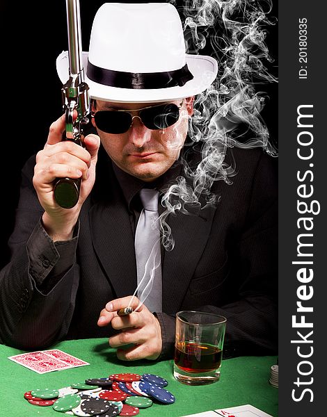 View of a gangster man playing some cards and poker, smoking a Cuban cigar. View of a gangster man playing some cards and poker, smoking a Cuban cigar.