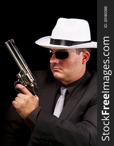 View of a dark suit gangster man holding a gun. View of a dark suit gangster man holding a gun.