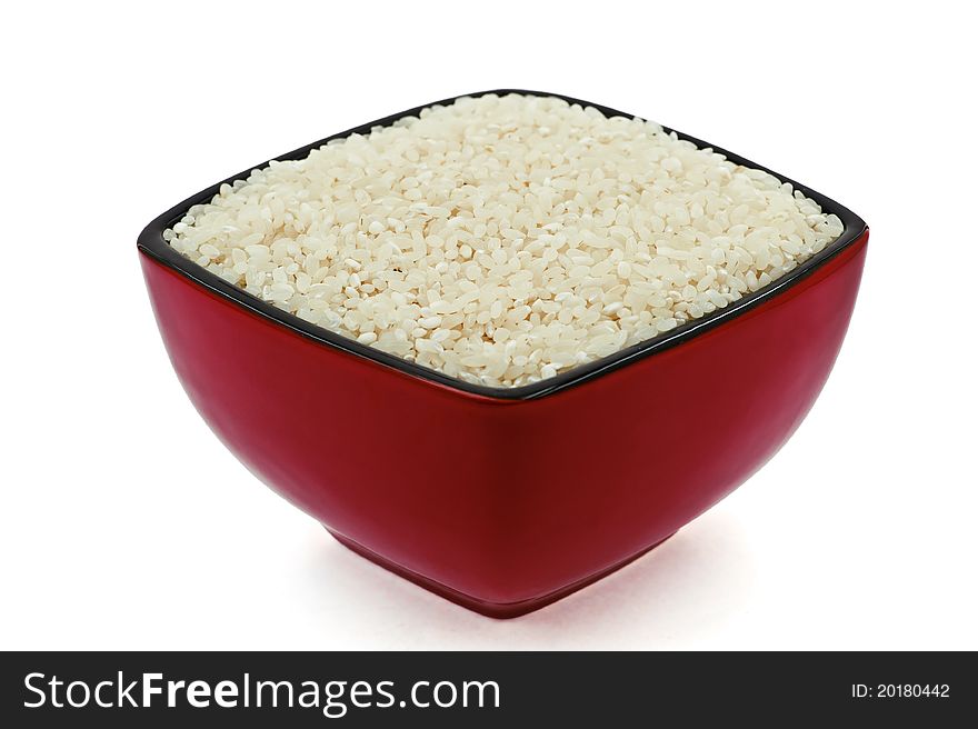 A red-black dish full of raw rice on the white background