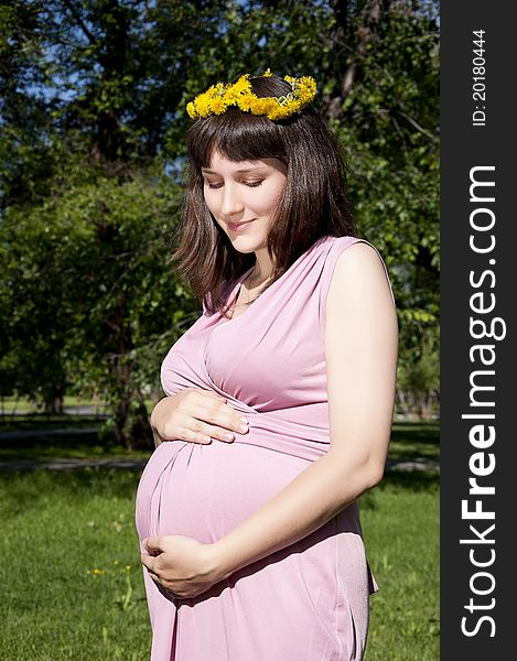 Portrait of the young beautiful girl in park, the girl embraces the stomach. Portrait of the young beautiful girl in park, the girl embraces the stomach