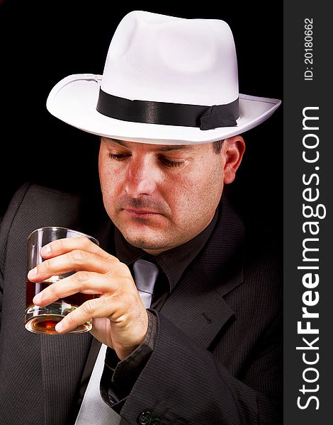 View of a gangster man with white hat drinking some liquor. View of a gangster man with white hat drinking some liquor.