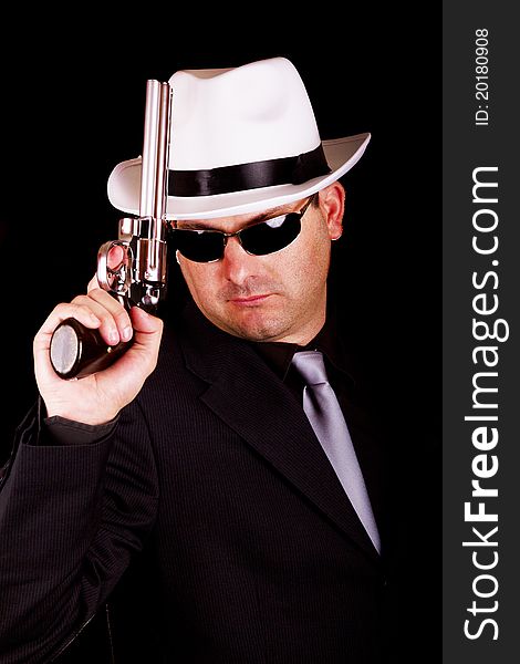 View of a dark suit gangster man holding a gun. View of a dark suit gangster man holding a gun.