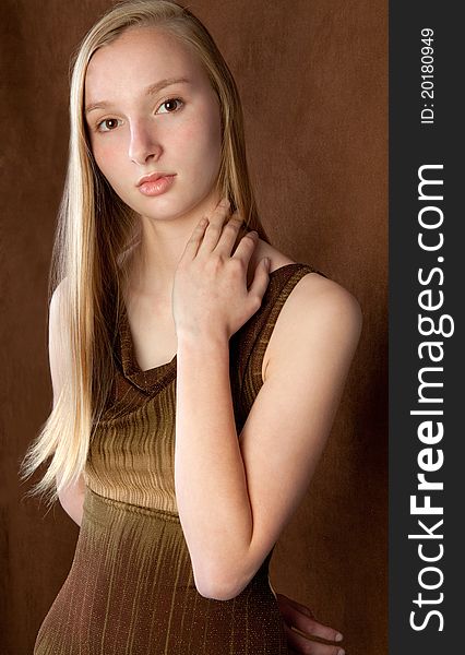 A portrait of a lovely teenager wearing a brown dress against a brown background. A portrait of a lovely teenager wearing a brown dress against a brown background