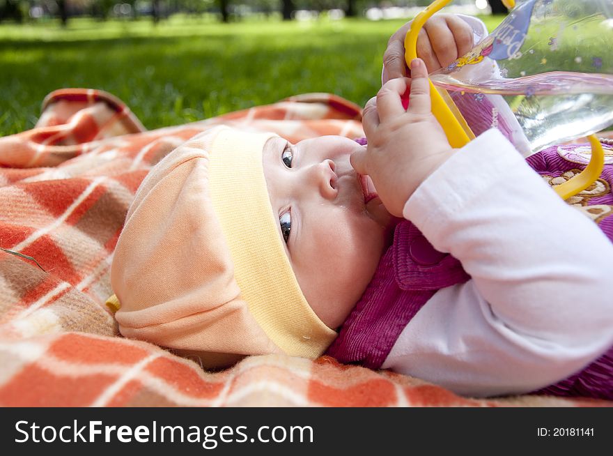 The portrait of the kid, lays on on a coverlet and drink water