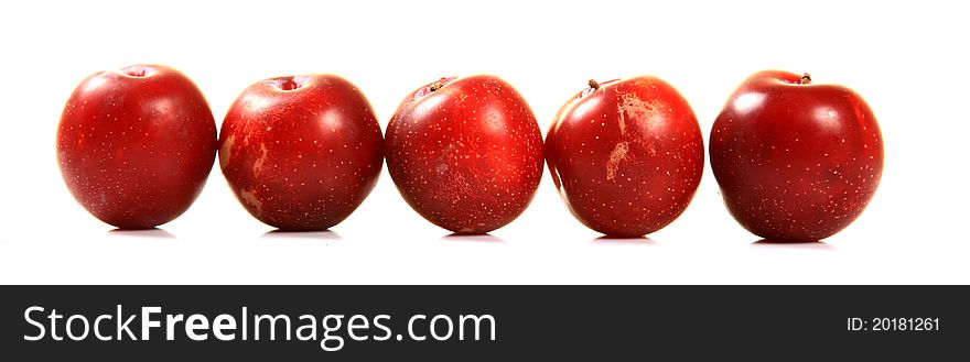 Ripe red plums over white background.