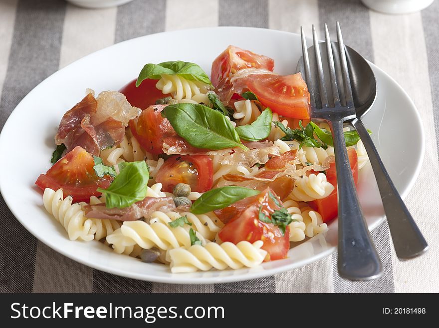 Pasta twists with tomatoes, prosciutto and basil in a bowl. Pasta twists with tomatoes, prosciutto and basil in a bowl