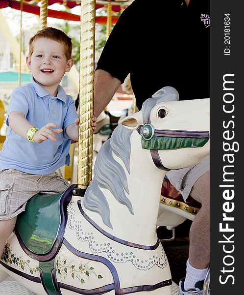 Young child enjoying riding a carousel horse. Young child enjoying riding a carousel horse.