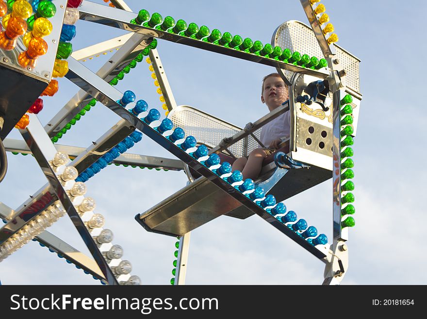 Young boy enjoying a ride on a ferris wheel at a carnival.