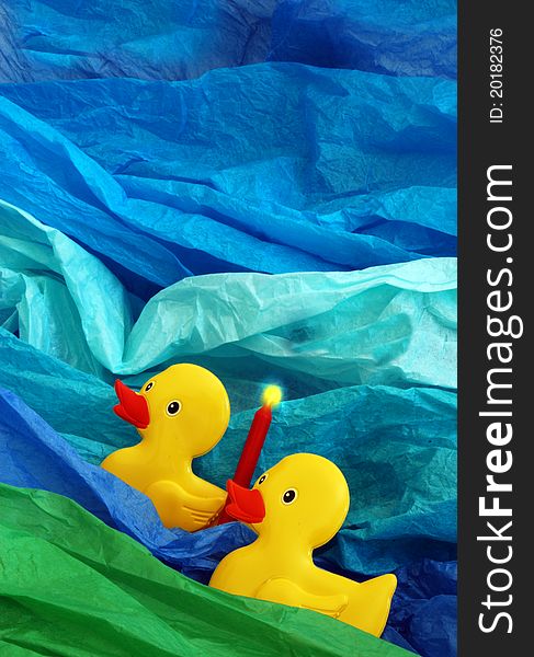 2 yellow ducks with a red candle on a blue aqua and green background. 2 yellow ducks with a red candle on a blue aqua and green background