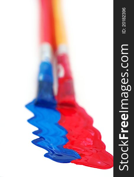 Two paintbrushes painting red and blue on white with shallow depth of field. Two paintbrushes painting red and blue on white with shallow depth of field