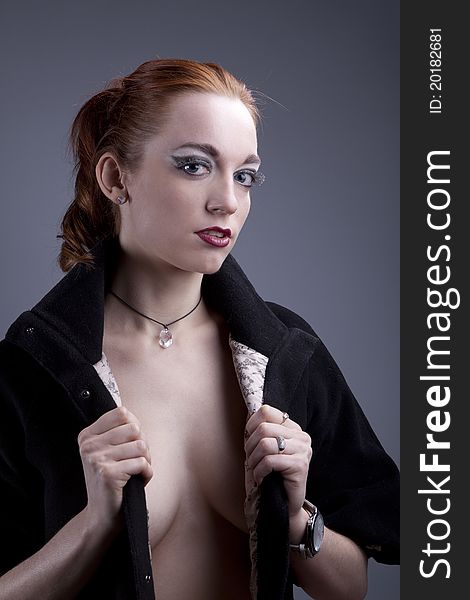 Portrait of a beautiful red-haired girl in a black coat with the vulgar make-up