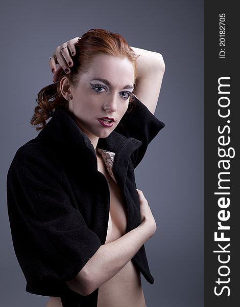 Portrait of a beautiful red-haired girl in a black coat with the vulgar make-up