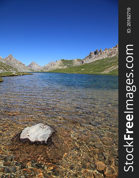 A translucent lake in mountains with a rock in foreground. A translucent lake in mountains with a rock in foreground.