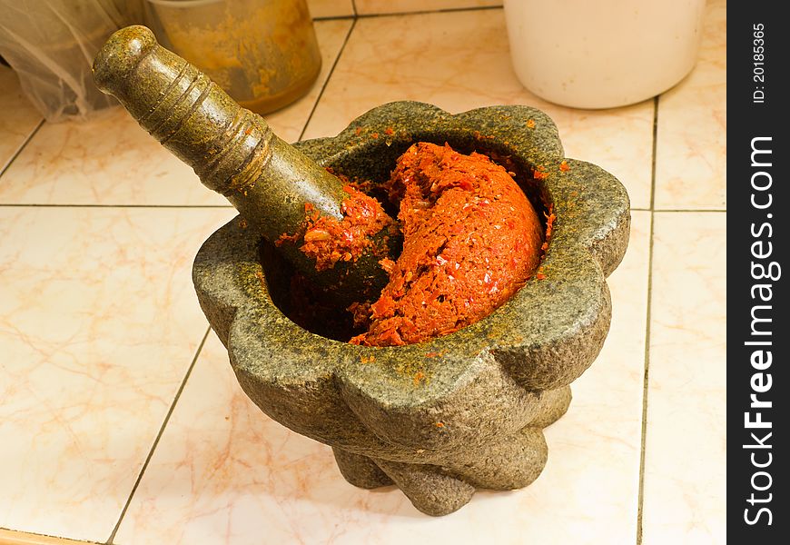 Stone mortar and pestle with red curry ingredient