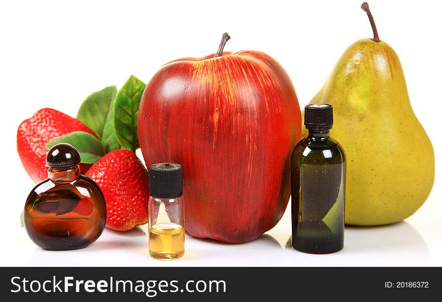 Fruit essence bottles with fruits over white background.