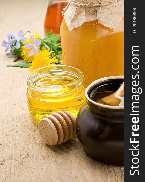 Honey in jars and flower on wood