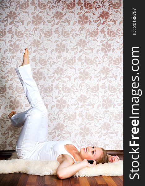 Beautiful young woman calling by phone on the floor of the house