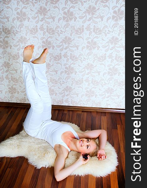 Beautiful young woman calling by phone on the floor of the house