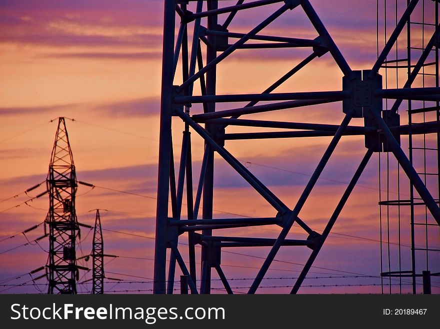 Tower poles for aerial lines on bright evening sky background