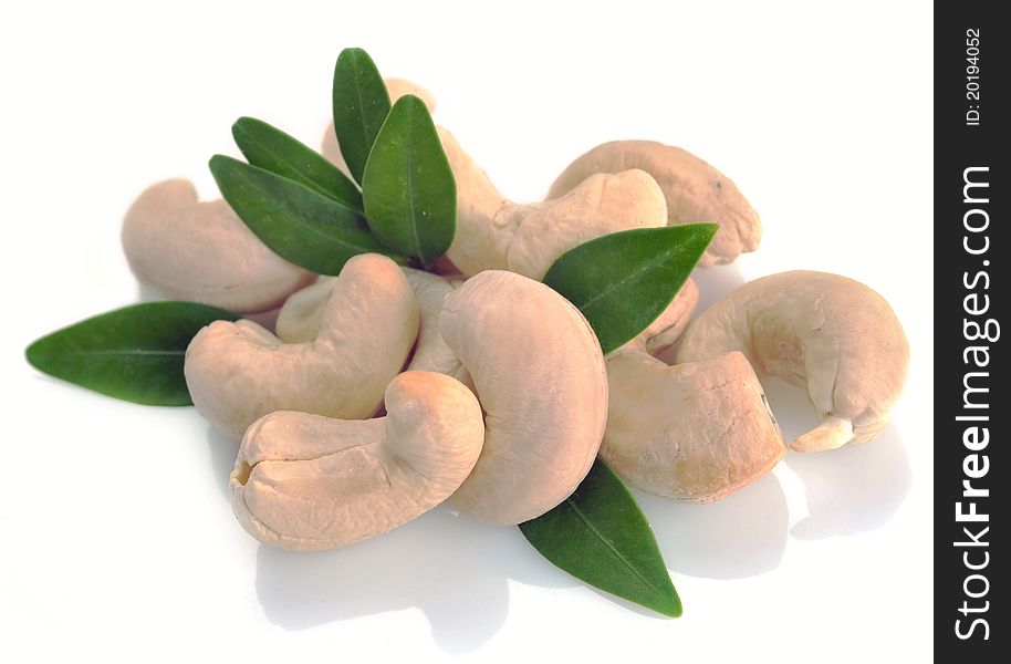 Ripe cashew nuts with leaves on a white background.