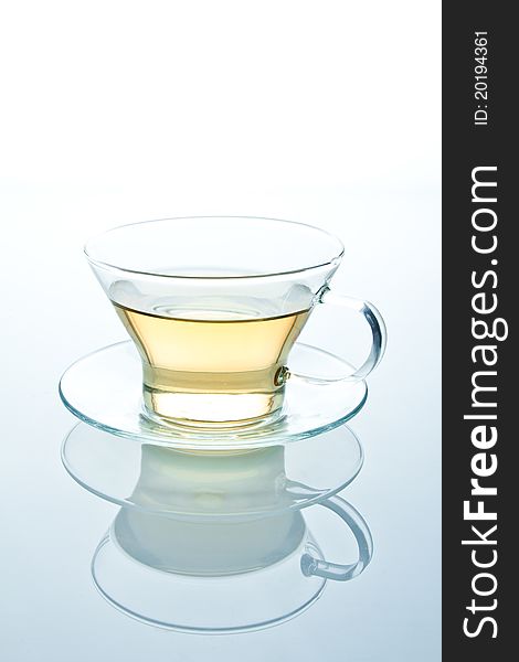 Isolated glass cup of tea or another liquid with reflection standing on a glass table