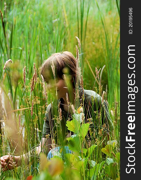 Boy hiding behind grass and leaves in a field. Boy hiding behind grass and leaves in a field.