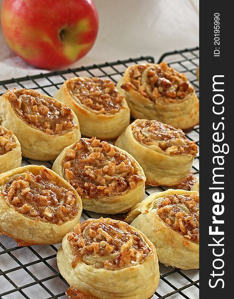 Apple pecan pastries on wire rack with red apple in background