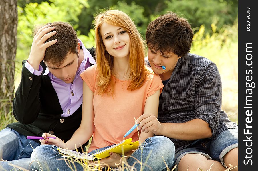 Three students at outdoor doing homework.