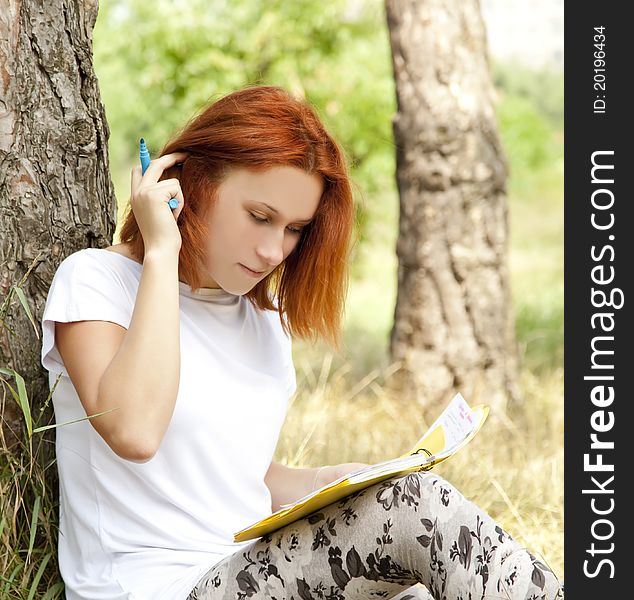 Redhead girl doing homework at outdoor.