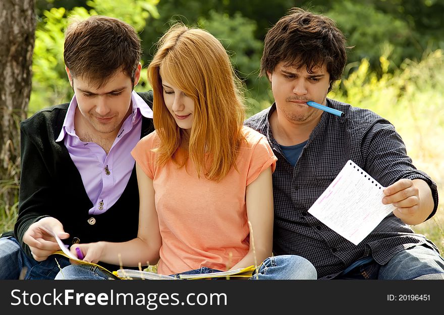 Three students at outdoor doing homework.