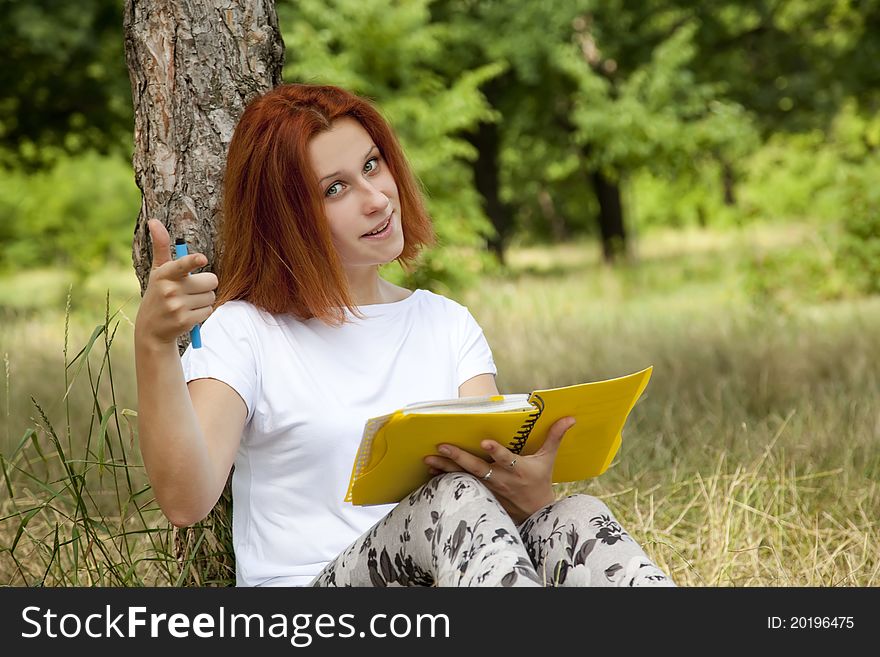 Redhead girl doing homework at outdoor.