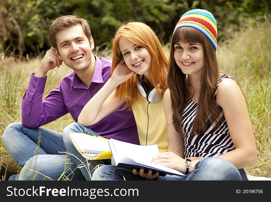 Three students at outdoor doing homework.