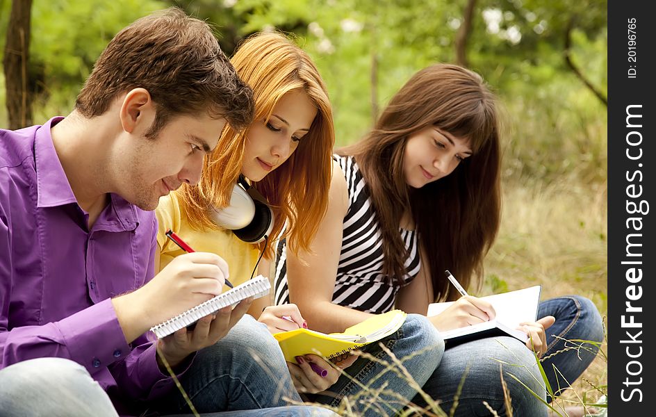 Three students at outdoor doing homework.