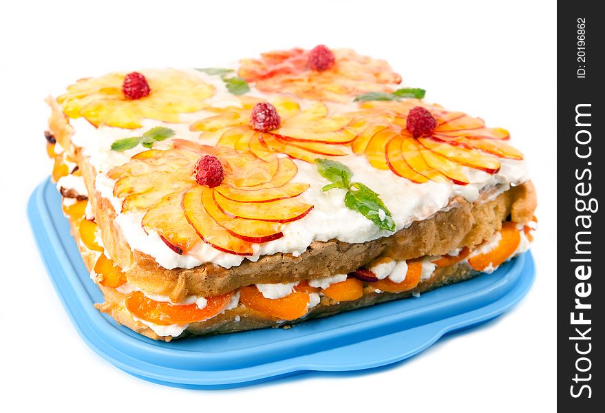 Cake with peaches and raspberries on a blue plate and a white background