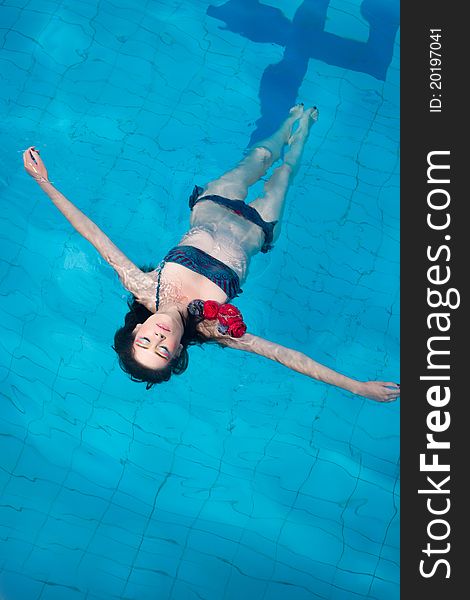 Woman In Bikini Floating In Swimming Pool