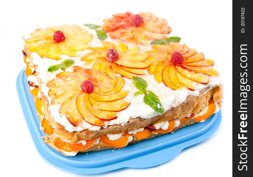 Cake with peaches and raspberries on a blue plate and a white background