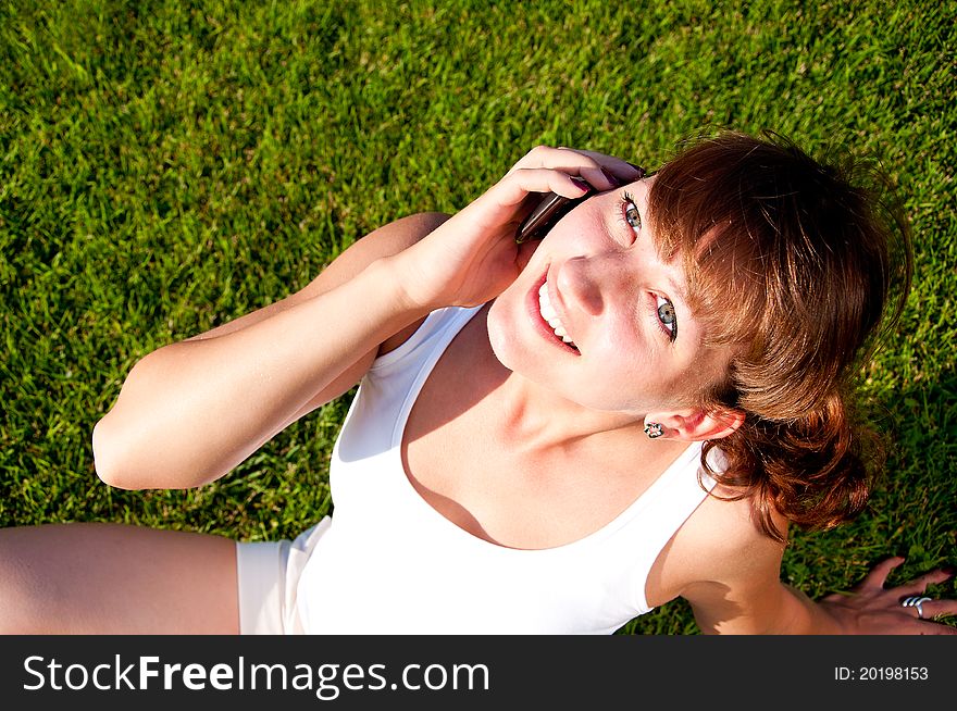 Portrait of young woman talking on phone, green grass background. Portrait of young woman talking on phone, green grass background