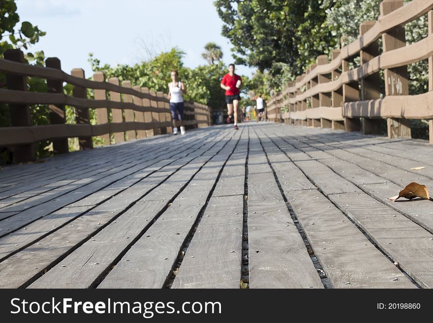 Male and female are jogging on a wooden bridge. Male and female are jogging on a wooden bridge