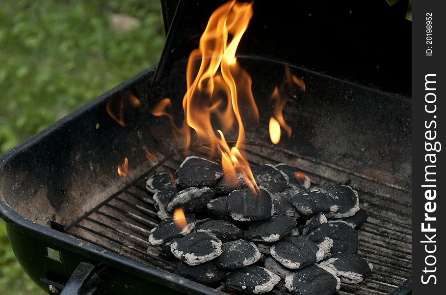 Charcoal has caught fire and is turning from black and cold to white hot and ready for cooking. Charcoal has caught fire and is turning from black and cold to white hot and ready for cooking.