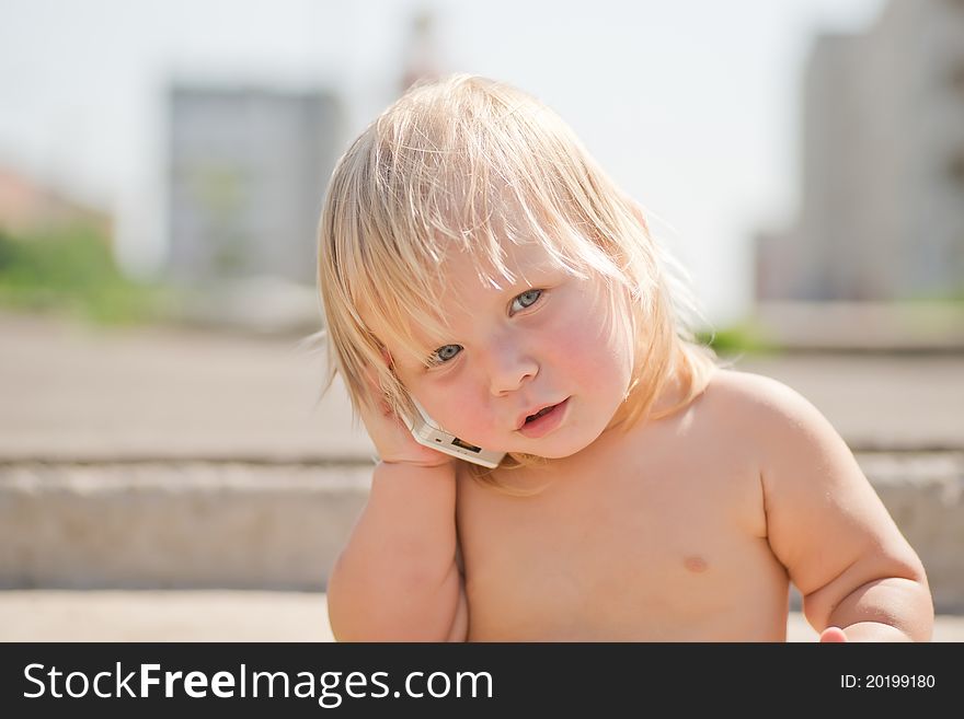 Adorable baby play with cell phone calling sitting on stairs on walk road