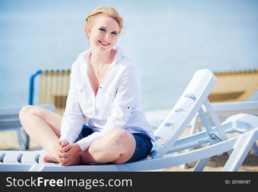 Beautiful woman sitting in chaise on the beach
