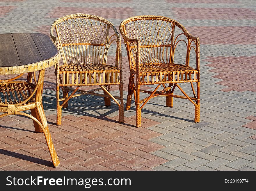 A pair of wicker chairs and table