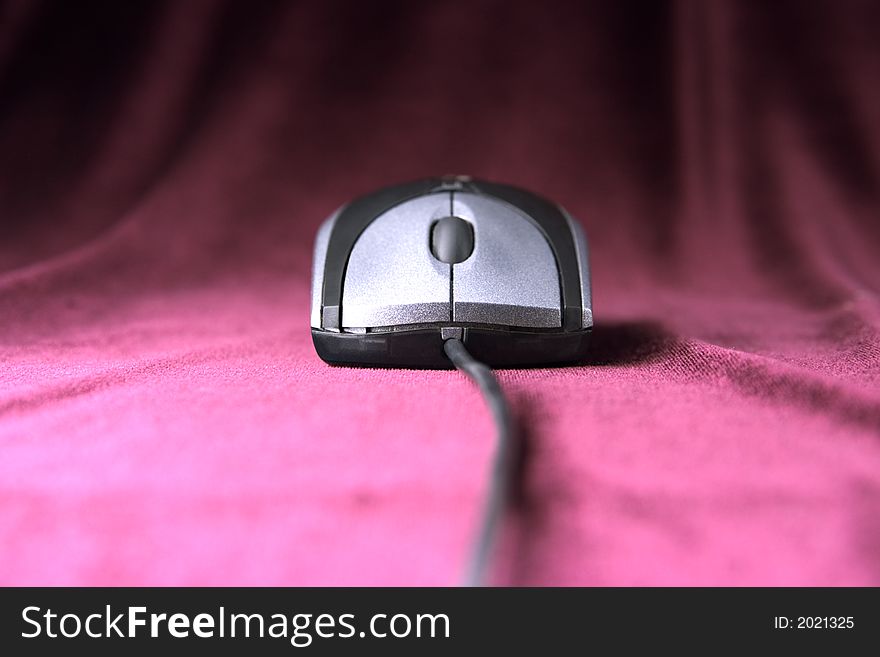 Computer mouse of grey color on purple velvet background